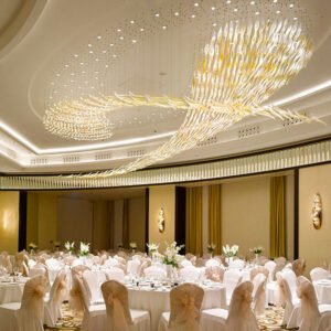 A breathtaking custom lighting installation in a luxurious hotel ballroom. The chandelier features a dynamic, flowing design that spans the curved ceiling, resembling a celestial river of light. Thousands of crystal or glass elements cascade in fluid patterns, with larger, more concentrated clusters forming distinct shapes reminiscent of comets or galaxies. The lighting elements blend warm golden hues with cooler white tones, creating a harmonious and enchanting glow. This magnificent chandelier is the centerpiece of an opulent ballroom set for a formal dinner, with round tables draped in white linens and chairs adorned with ivory covers and golden sashes. The room's decor, including ornate wall sconces and a sophisticated color palette, complements the grandeur of the lighting fixture, transforming the space into a magical setting for high-end events and celebrations.