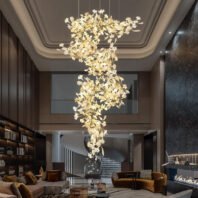 Breathtaking branch chandelier cascades through a two-story living area, featuring golden branches adorned with illuminated white floral elements. The chandelier's intricate design creates a stunning focal point, complementing the room's elegant decor. Set against a backdrop of warm neutral tones, dark marble accents, and plush furnishings, this exquisite branch chandelier adds a touch of organic luxury. Its soft, warm glow enhances the sophisticated ambiance, lighting up the space from the ornate ceiling to the modern seating area below. The chandelier's flowing form draws the eye upward, emphasizing the room's impressive height and architectural details.