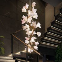 Captivating branch chandelier illuminates a contemporary stairwell, featuring delicate white and pink flower-shaped lights. Golden branches gracefully support the blooming fixtures, creating a stunning contrast against the dark, industrial-style interior. The chandelier cascades down, complementing the sleek floating staircase with glass railings and LED-lit steps. This exquisite branch chandelier serves as a focal point, softening the stark lines of the concrete walls and metal accents. The warm glow of the floral lights adds an organic, ethereal touch to the modern space, beautifully blending nature-inspired design with urban sophistication.