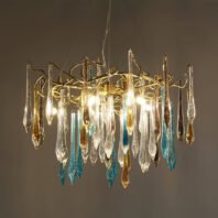 Ornate chandelier with golden branches supporting colorful glass icicles in clear, blue, and amber. Lit bulbs cast a warm glow through the textured glass droplets. The fixture hangs against a neutral background, showcasing its intricate design and luminous quality.