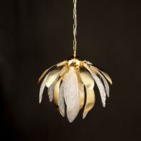 An exquisite pendant chandelier illuminated against a dark background, showcasing a harmonious blend of gold and crystal elements. The fixture resembles a blooming flower or artichoke, with alternating gold and crystal petals radiating outward from a central core. The gold petals have a smooth, ribbed surface with a warm metallic sheen, curving gracefully outward. The crystal petals are clear and intricately textured with a pattern reminiscent of delicate leaf veins, adding a translucent and ethereal quality to the design. The light emanating from within the chandelier highlights the intricate details of both the gold and crystal components, creating a warm, inviting glow. The crystal elements catch and refract the light, producing a soft, sparkling effect. The chandelier is suspended by a delicate gold chain, adding to its refined appearance. This piece masterfully combines organic, nature-inspired forms with luxurious materials, resulting in a striking blend of contemporary design and classic elegance. The illuminated chandelier appears to float in the darkness, emphasizing its role as both a functional light source and a captivating decorative element, perfect for creating a focal point in any sophisticated interior space.