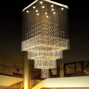 A stunning large chandelier showcases innovative custom lighting design for upscale hotels. This big chandelier features a square base with multiple lights, from which thousands of crystal tubes descend in a multi-tiered pyramid shape. The chandelier's warm, golden glow creates a mesmerizing waterfall effect of light against the dark ceiling. Suspended in a grand atrium space, it illuminates ornate railings on upper floors and a central column below. This unique hotel chandelier transforms the space into a dazzling display of luxury and elegance, demonstrating how bespoke lighting can elevate high-end hospitality environments to create unforgettable guest experiences.