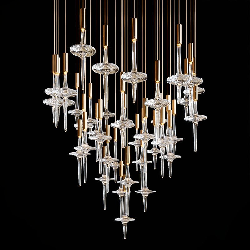 A stunning large hotel chandelier showcasing innovative custom lighting design. This big chandelier features numerous glass elements resembling elongated spindles or hourglasses, each consisting of a blown-glass disc with tapered crystal extensions. The glass components are suspended at varying heights by thin golden rods, creating a dramatic cascading effect against a dark background. The arrangement forms a teardrop or inverted pyramid shape, with the elements clustered more densely at the bottom. The interplay of light on the crystal surfaces adds sparkle and depth to the design. This sophisticated piece exemplifies high-end custom lighting, perfect for creating a captivating focal point in luxurious hotel spaces, blending artistry with functionality to transform the ambiance with its ethereal presence.