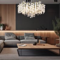 A contemporary living room featuring a stunning crystal disc chandelier as the centerpiece. The room has a sophisticated color palette of dark gray, light wood, and neutral tones. A large gray sectional sofa occupies the foreground, accompanied by a sleek wooden coffee table. The walls combine dark gray panels with light wood accents, creating a striking contrast. Ambient lighting under the wood paneling adds warmth to the space. The oval-shaped chandelier, composed of numerous white and clear crystal discs with gold accents, hangs prominently above, casting a soft glow. Potted plants and minimalist decor elements complete the modern, elegant aesthetic of the room.