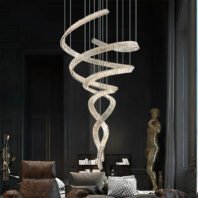 A large chandelier featuring custom lighting design with a spiraling, ribbon-like structure. This big hotel chandelier showcases an intricate, twisting formation of crystal-clear elements, creating a mesmerizing focal point against a dark interior. The custom lighting piece casts a soft, ethereal glow, contrasting beautifully with the moody ambiance of the room. Suspended by thin wires, it appears to float gracefully above luxurious furniture. This spectacular chandelier offers a perfect blend of modern sculpture and functional lighting for upscale hotel spaces.