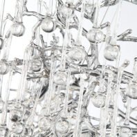 A close-up view of an elaborate glass chandelier featuring a complex network of clear glass elements. The image shows intertwining glass branches or stems forming an organic, tree-like structure. Hanging from these branches are numerous thin glass rods of varying lengths, each ending in a small spherical glass droplet. The droplets have a subtle, frosted appearance, suggesting they might contain air bubbles or have a textured surface. The glass components are highly reflective and transparent, creating a multitude of light refractions and reflections. The intricate arrangement of the glass pieces gives the chandelier a natural, crystalline appearance, reminiscent of ice formations or a abstract representation of raindrops on branches. This detailed view highlights the craftsmanship and complexity of the chandelier's design, showcasing its blend of organic forms with modern, luxurious materials.