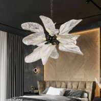 A contemporary bedroom featuring a striking chandelier with large, translucent glass leaves. The chandelier hangs above a bed with a tufted headboard. Dark walls contrast with a geometric wood-paneled accent wall behind the bed. The room's design blends natural elements with modern luxury, creating an elegant and sophisticated atmosphere.