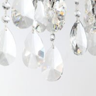 A detailed close-up view of crystal chandelier pendants against a light background. The image showcases various sizes and shapes of crystal droplets, primarily featuring large teardrop-shaped crystals. These teardrops are intricately faceted, creating multiple surfaces that brilliantly refract light. Smaller round crystal beads can be seen connecting some of the larger pieces. The crystals display a dazzling array of light effects, including rainbow-like prisms and bright white reflections. The precision cut of the crystals is evident, with sharp edges and smooth surfaces that enhance their luxurious appearance. Light hitting the crystals at different angles produces a mesmerizing interplay of sparkles, shadows, and refractions. This intimate view of the chandelier components emphasizes the high-quality craftsmanship and the luminous beauty of the crystals, suggesting that the full chandelier would be a stunning and opulent lighting fixture, capable of adding glamour and elegance to any sophisticated interior space.