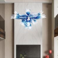 A striking custom lighting installation featuring a large chandelier composed of unique glass elements. This chandelier showcases an array of elongated, petal-like glass pieces arranged in a circular pattern, resembling a blooming flower. Each glass petal transitions from clear at the tip to a deep blue at the base, creating a stunning ombre effect. The custom lighting piece is suspended by thin wires in a modern interior setting with neutral tones. It hangs above a sleek fireplace, contrasting beautifully with the room's minimalist design. The chandelier's organic, fluid form and vibrant blue hues make it a captivating focal point, adding a touch of artistic elegance to the contemporary space.